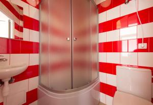 W wyłożonej czerwono-białymi kafelkami łazience znajduje się toaleta i umywalka. w obiekcie Mini Smart Apartments on Shpytalna 13- Economy Apartment w Lwowie