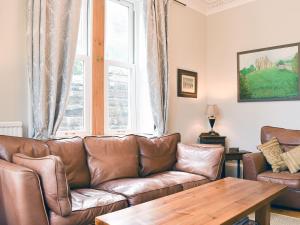 a living room with a brown leather couch and a table at Grosmont Villa in Grosmont