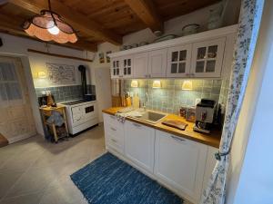 Una cocina con gabinetes blancos y un fregadero. en Villa Amalia, centrum Banska Stiavnica, parkovanie pre 2 auta, velka zahrada s krbom, cela Villa Amalia pre 16 osob alebo samostatne nezavisle prve podlazie Villa AMA pre 8 osob alebo samostatne nezavisle podkrovie Villa LIA pre 8 osob,prístup cez PIN-kód, en Banská Štiavnica
