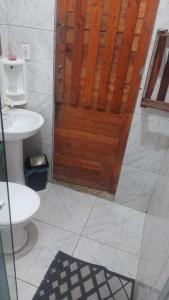 a bathroom with a toilet and a wooden door at Casa da Família in Magé