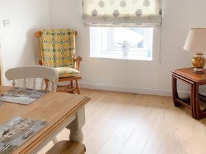 a living room with a table and a chair and a window at Snowdrop Cottage in Fishguard