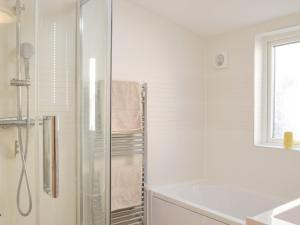 a white bathroom with a shower and a sink at Snowdrop Cottage in Fishguard