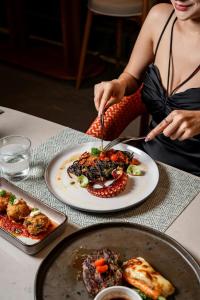 a woman sitting at a table with a plate of food at Veranda Resort Phuket, Autograph Collection in Panwa Beach