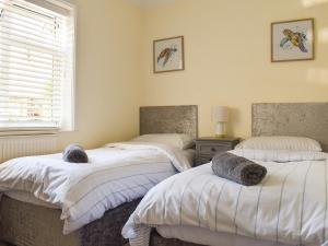 Sunbury Cottage في Clanfield: سريرين توأم في غرفة بها نافذة +3 صور