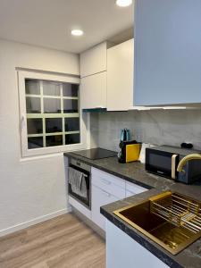 a kitchen with white cabinets and a sink at O Refúgio dos Ferreiros in Guarda +8 photos