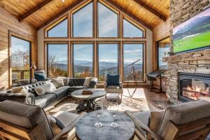 a living room with a fireplace and a large window at Ridgetop Cabin Retreat w Pool Hot tub & Theater in Sevierville +65 photos