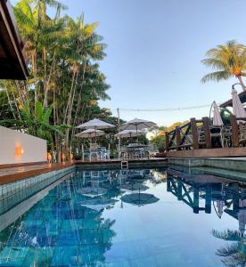 a swimming pool with chairs and umbrellas in a resort at Condomínio Valls Village in Itacaré