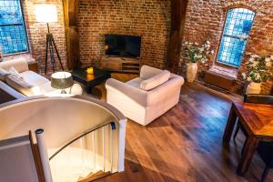 a living room with white furniture and a brick wall at De Gevangentoren Suite in Vlissingen