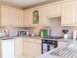 a kitchen with wooden cabinets and a stove top oven at Princes Gate Cottage in Templeton