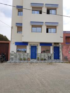 ein weißes Gebäude mit blauen Türen davor in der Unterkunft Appartements Hajar in Oualidia