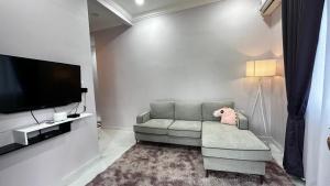 a living room with a couch and a flat screen tv at Santai Rhuteng Homestay in Kampong Ru Sepuloh