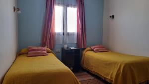 Dos camas en una habitación pequeña con ventana. en La Nona, en El Carmen