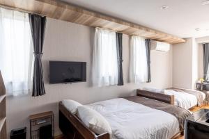 a bedroom with two beds and a flat screen tv at Flex cella Tsukisamu in Sapporo