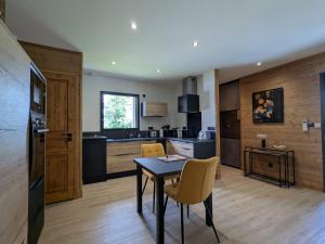 a kitchen and dining room with a table and chairs at Lodge élégant avec spa privatif et espace bien-être - FR-1-582-530 in Le Chambon-sur-Lignon