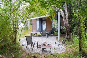 PerwillowenHill Creek Tiny House 3 by Tiny Away的树林里有椅子和桌子的房子