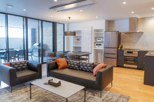 a living room with two couches and a kitchen at Wadano Gateway Suites & Apartments in Hakuba