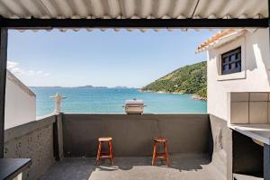 two stools on a balcony with a view of the ocean at Beira-Mar Guest House in Arraial do Cabo
