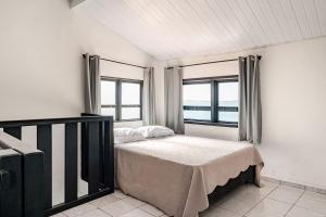 a bedroom with a bed and two windows at Beira-Mar Guest House in Arraial do Cabo