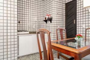 a glass table with two chairs and a black door at Beira-Mar Guest House in Arraial do Cabo