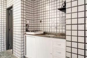 a bathroom with a sink and white tiled walls at Beira-Mar Guest House in Arraial do Cabo +61 photos
