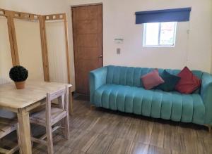 a blue couch in a living room with a table at Cuatro Rumbos Hospedaje in San Baltasar
