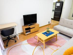 Yadachōにある大曽根駅から徒歩5分人工温泉が24時間楽しめてナゴヤドームまで徒歩で行く事が出来ますのソファとテレビのあるリビングルーム