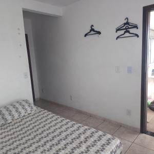 a bedroom with a bed and three hangers on the wall at Dona Maria - Quartos in Rio Grande da Serra