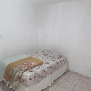 a bed in a room with a white wall at Dona Maria - Quartos in Rio Grande da Serra +5 photos