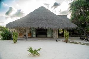 a hut with a straw roof on a beach at Sardine Beach Rote in Pulau Helihana