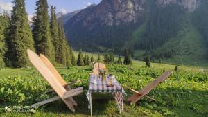 a table and two chairs with a table and a mountain at Ernis Yurt Camp in Mineralʼnyy Istochnik Altyn-Arasan +21 photos