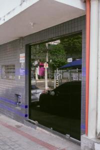 a store window with a reflection of a car in it at kitnet no centro de Betim in Betim