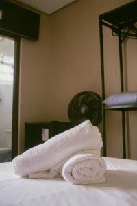 a stack of towels sitting on top of a bed at kitnet no centro de Betim in Betim