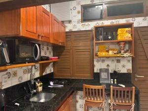 een keuken met houten kasten en een aanrechtblad bij 05 Kitnet próximo da praia com ar-condicionado in Maceió