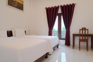 a hotel room with two beds and a window at Sipanya Guesthouse in Muang Phônsavan