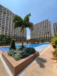 a swimming pool with a palm tree and two large buildings at Studio Condo in Saekyung Village One Phase3 in Lapu Lapu City