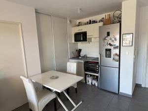 a small kitchen with a table and a refrigerator at Appartement Perpignan in Perpignan