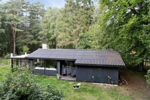 a black house in the middle of a yard at Forest Vibe And Idyll On Møn in Stege