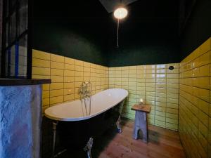 a bathroom with a tub and green and yellow tiles at Rustic Holiday Apartment, Lovingly Restored in Rambin