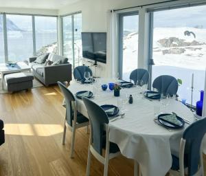 a dining room with a table and chairs and a television at Vestavindshagen - Modern Gem By Sea And Hills in Leirvåg