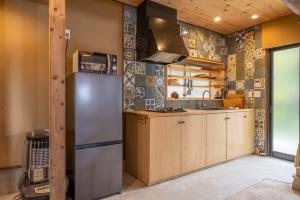 cocina con nevera de acero inoxidable y azulejos en Garden Planet, en Minamiboso