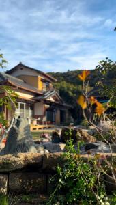 una casa con una pared de piedra frente a una casa en Garden Planet, en Minamiboso