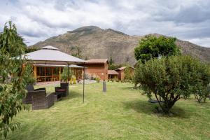 a house in a field with a mountain in the background at Unuwasi Hotel & Villa in Calca