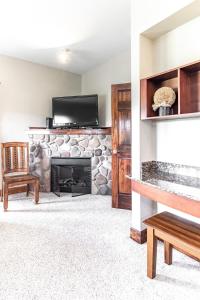 a living room with a stone fireplace and a flat screen tv at Cozy Retreat 2BR Condo with Jacuzzi & Indoor Pool in Pigeon Forge