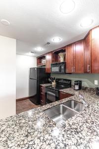 a kitchen with wooden cabinets and a stainless steel sink at Cozy Retreat 2BR Condo with Jacuzzi & Indoor Pool in Pigeon Forge +57 photos