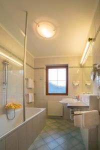 La salle de bains est pourvue d'une baignoire, de 2 lavabos et d'une douche. dans l'établissement Hotel Neuwirt, à Kirchdorf in Tirol