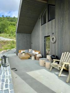 a patio with a couch and chairs on a building at Architect Cabin With Strandafjellet View in Stranda