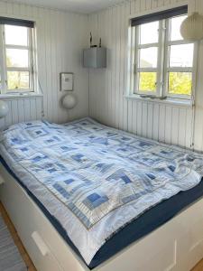 a large bed in a room with two windows at Charming Summer House Near Dalbybugten in Mesinge
