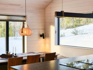 a dining room with a table and a large window at Architect-Designed Cabin At Hallandsfjellet in Rødberg +15 photos