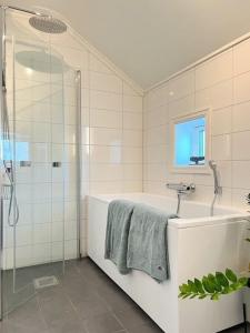 a bathroom with a shower and a tub and a sink at Modern Beach House On Car-Free Vestre Sandøya in Kilen