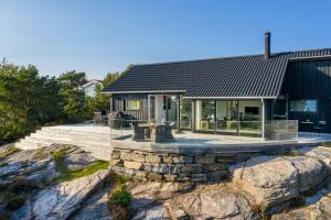 una casa en una colina rocosa con una mesa delante en Seaside Cabin With Ocean View And Sunny Terrace, en Søgne 8 fotos más